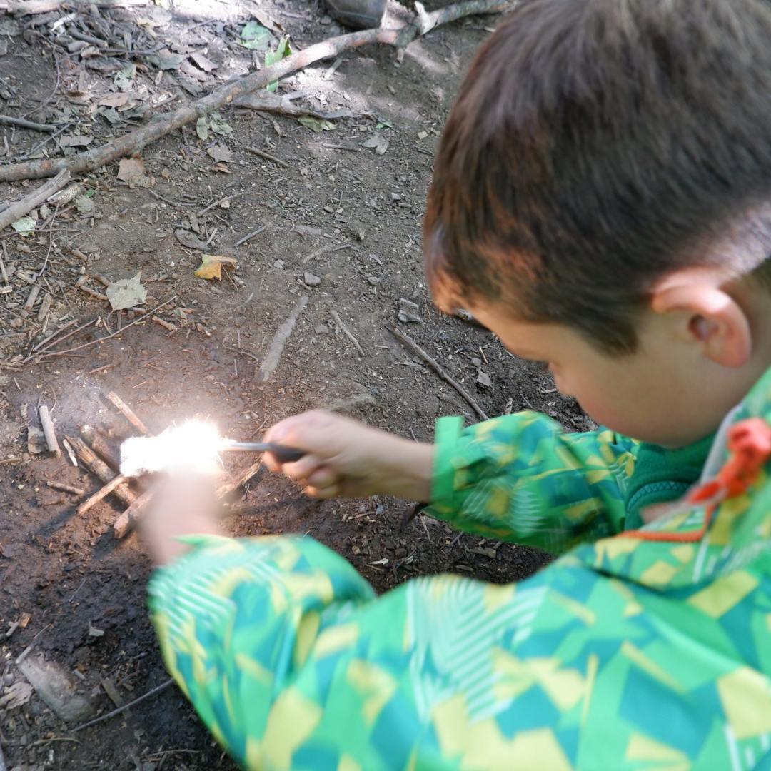 Child with a firelighter creating a spark to light a fire