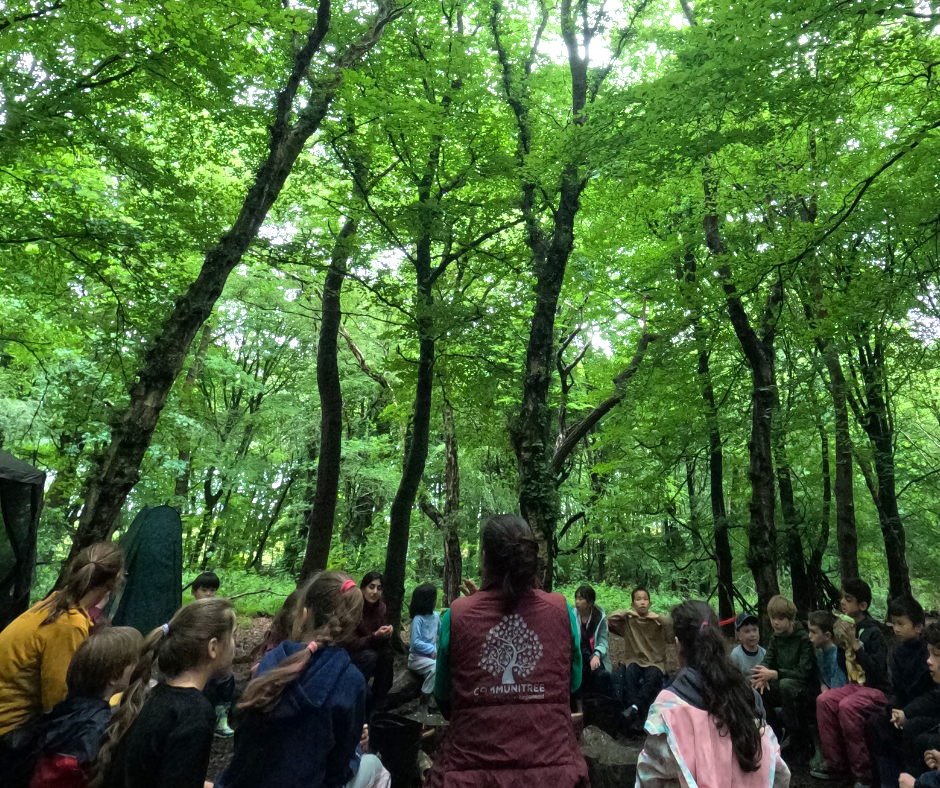 Children sat in a circle around the fire pit in Heaton Park Manchester at Communitree Holiday Club