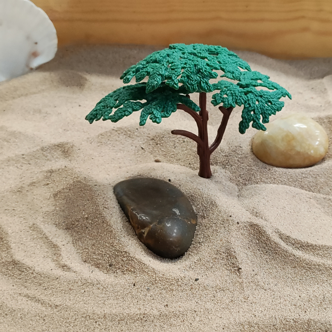 Stones and plastic tree placed in a sand tray