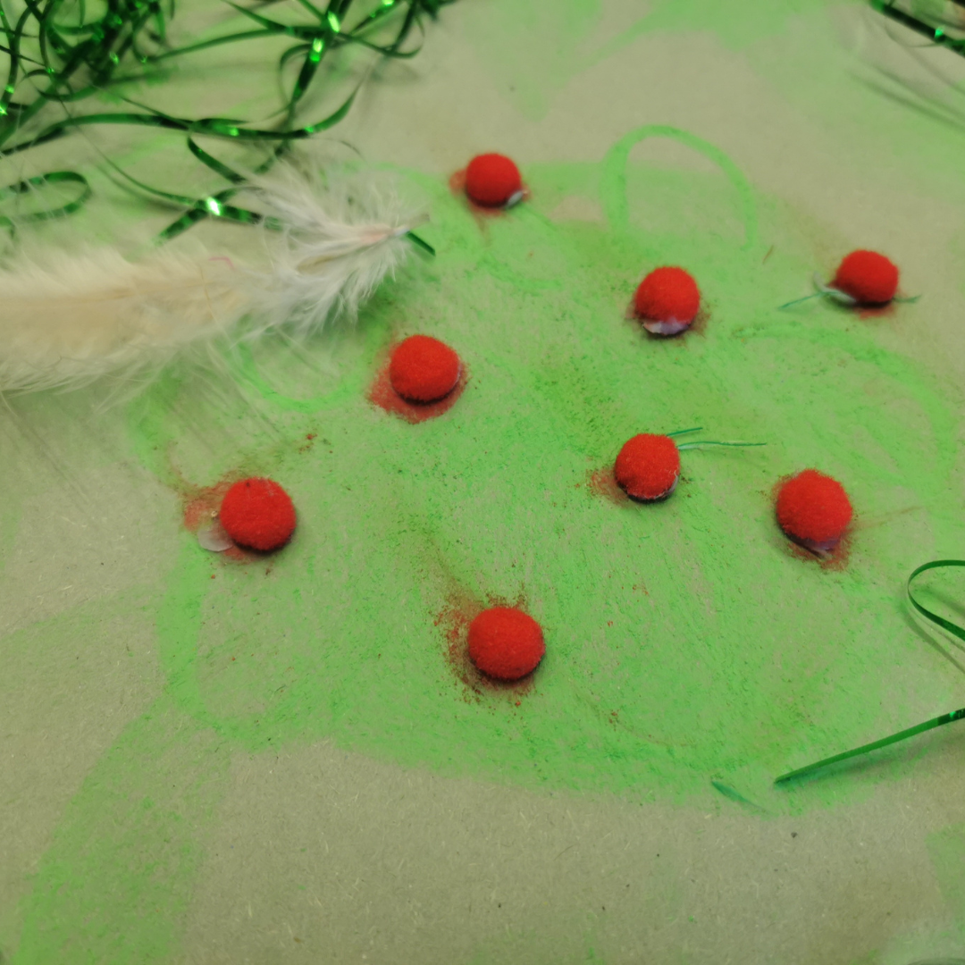 Therapeutic play toolkit - Red pom poms, green tinsel and feather
