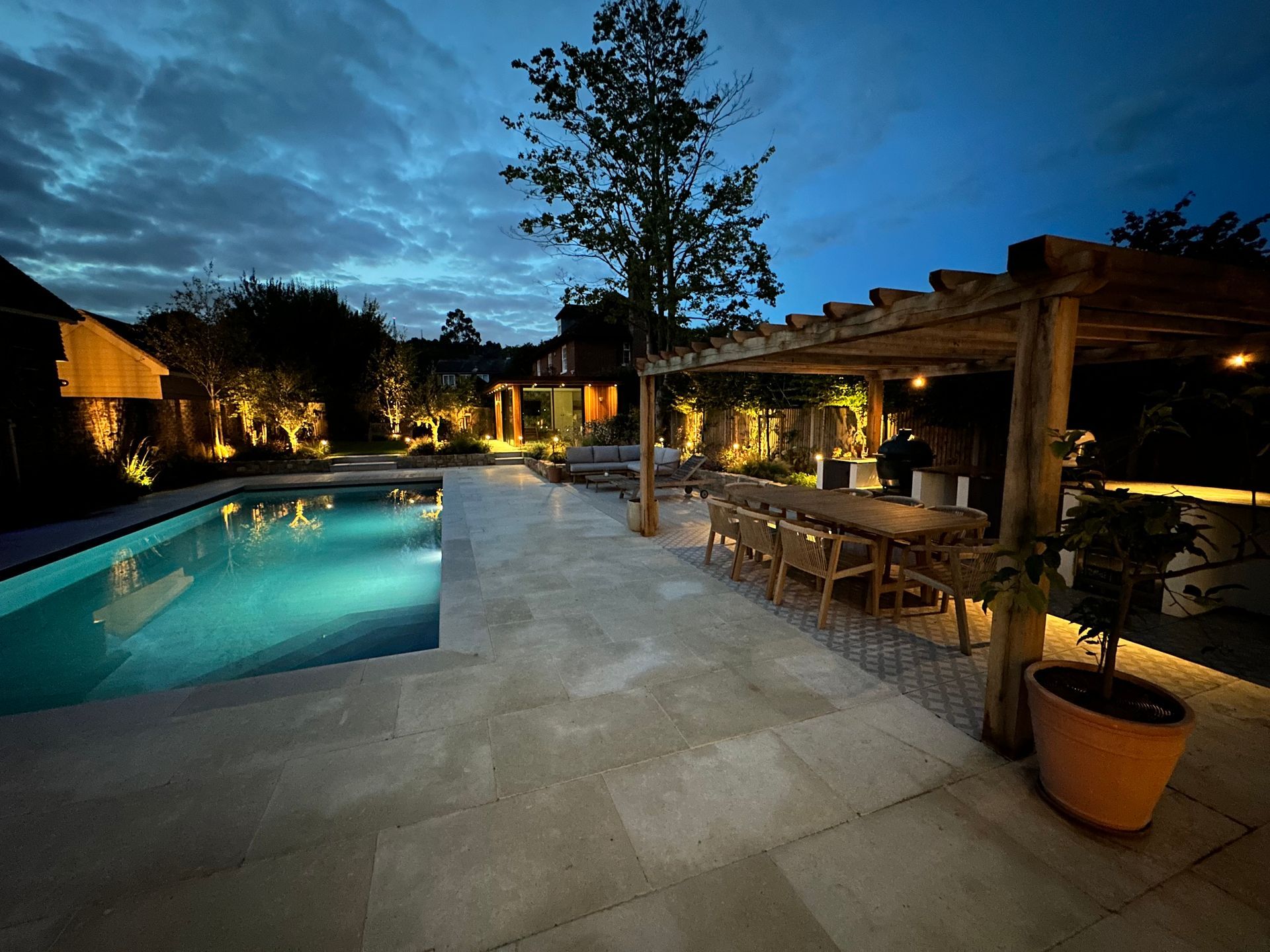 Night time swimming pool showcasing LED up lights of accent plants around patio