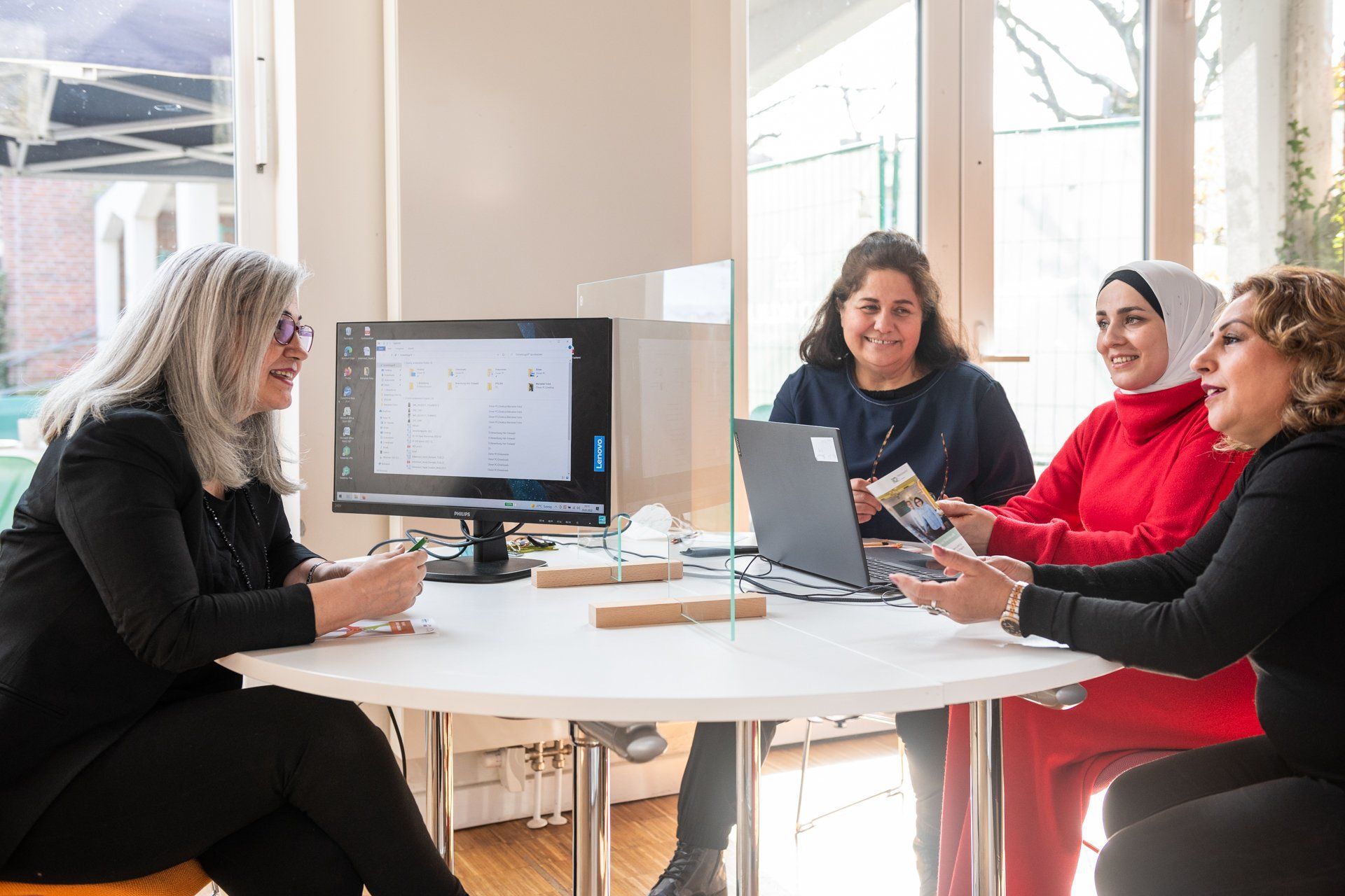 Eine Frau berät drei Frauen am Tisch