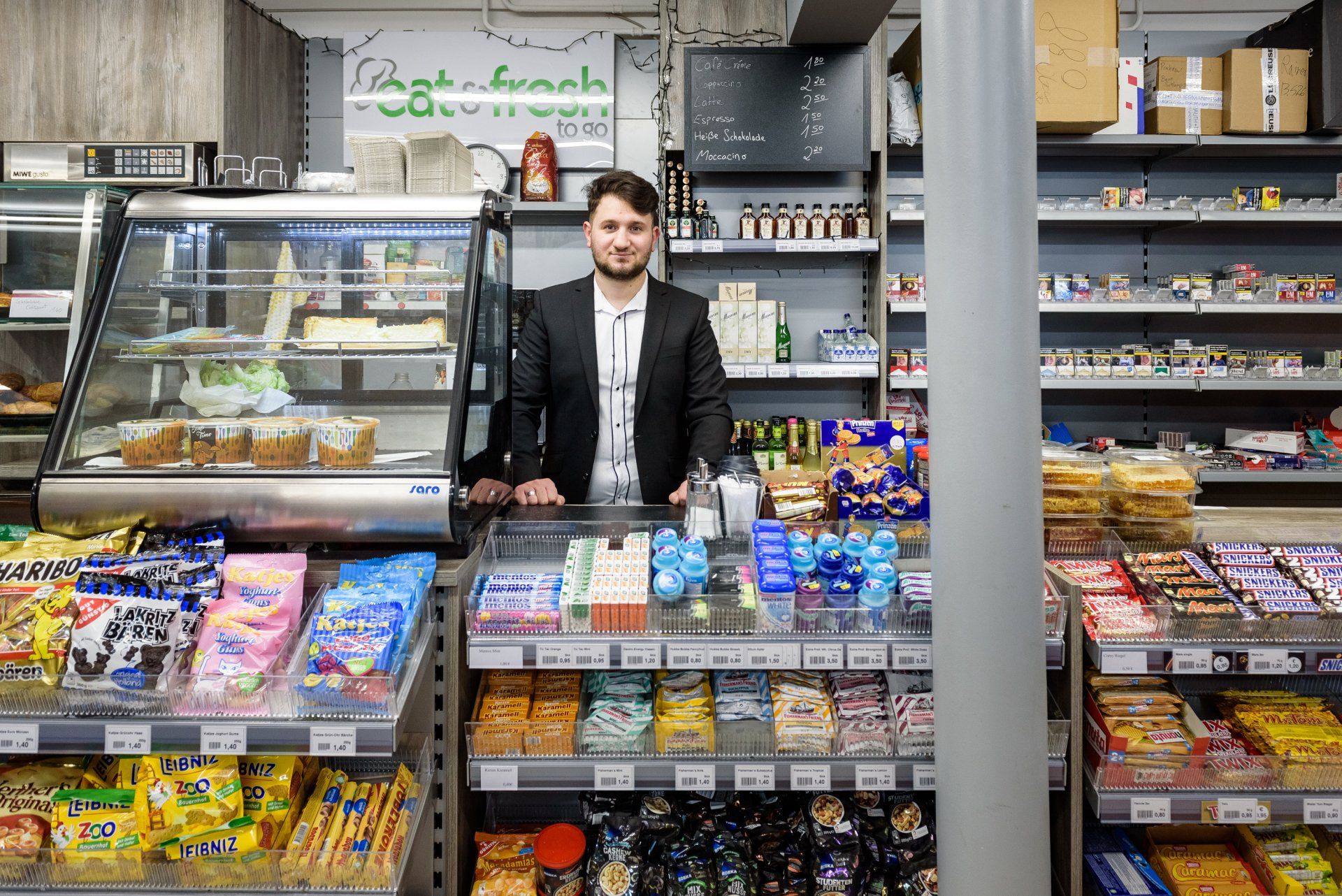 Ein Mann steht hinter einem Verkaufstresen mit Süßigkeiten.
