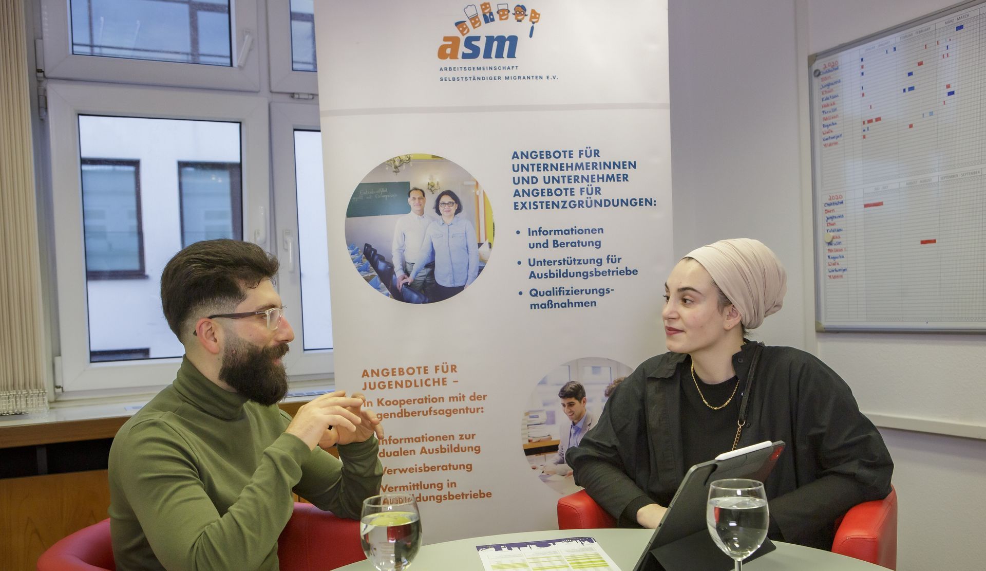 Mentorin und Mentee Eine Mentorin und ihr Mentee sitzen am Tisch mit Büchern.