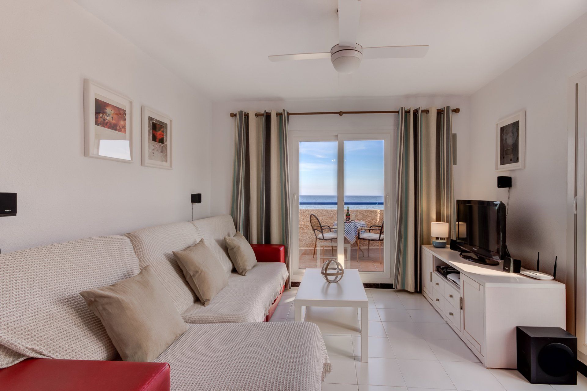 the living room with large sofa and patio doors looking out to sea