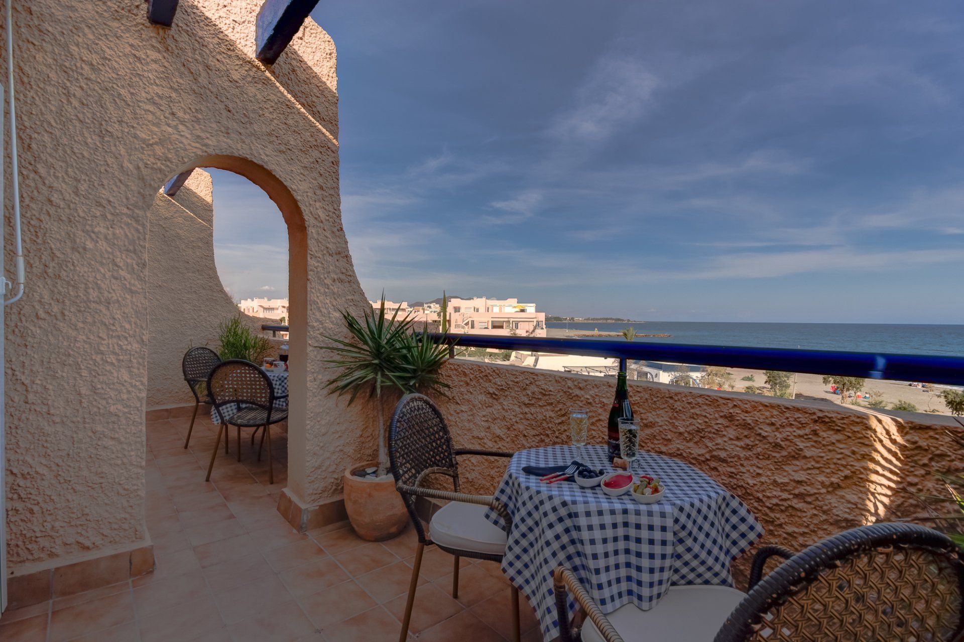 the terrace from the living connects to the bedroom terrace via an archway with a small table and chairs on each and a sea view