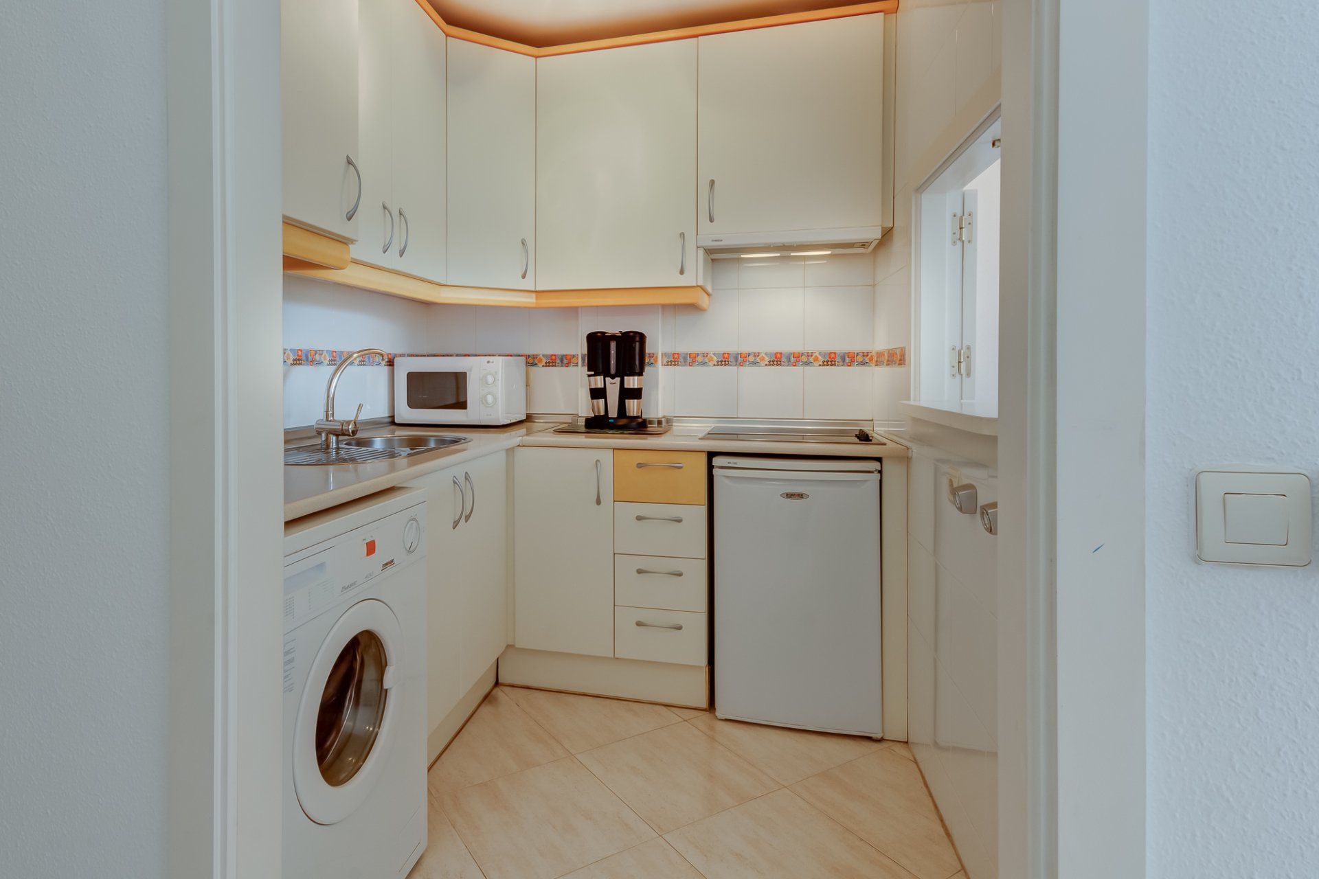 kitchen with white units and yellow trim and cream tiled floor