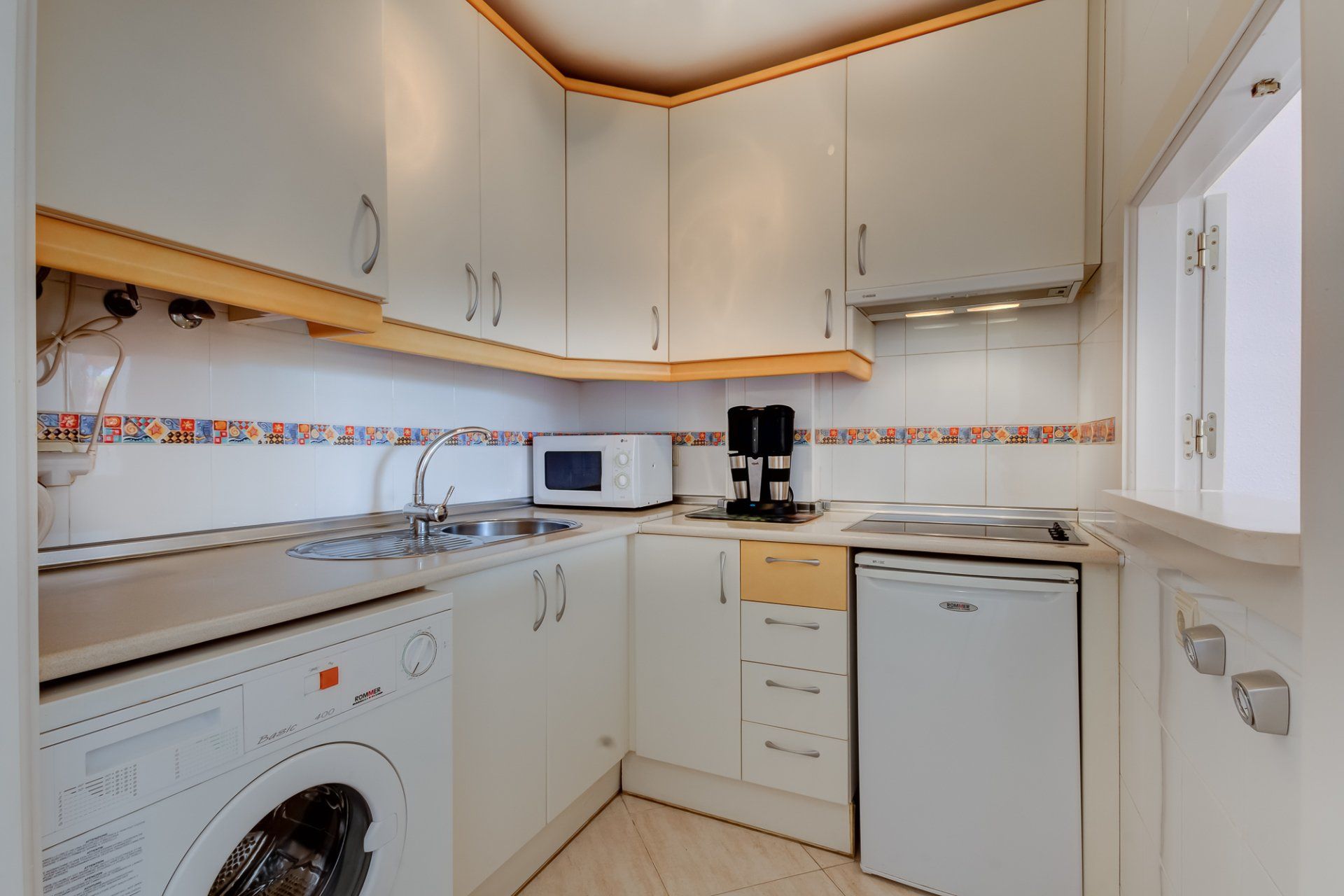 kitchen with white units and yellow trim and a serving hatch to the right
