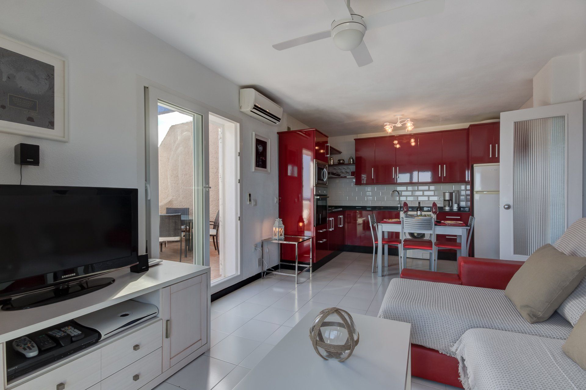 coffee table with glass globe ornament in foreground and red high gloss kitchen in the background