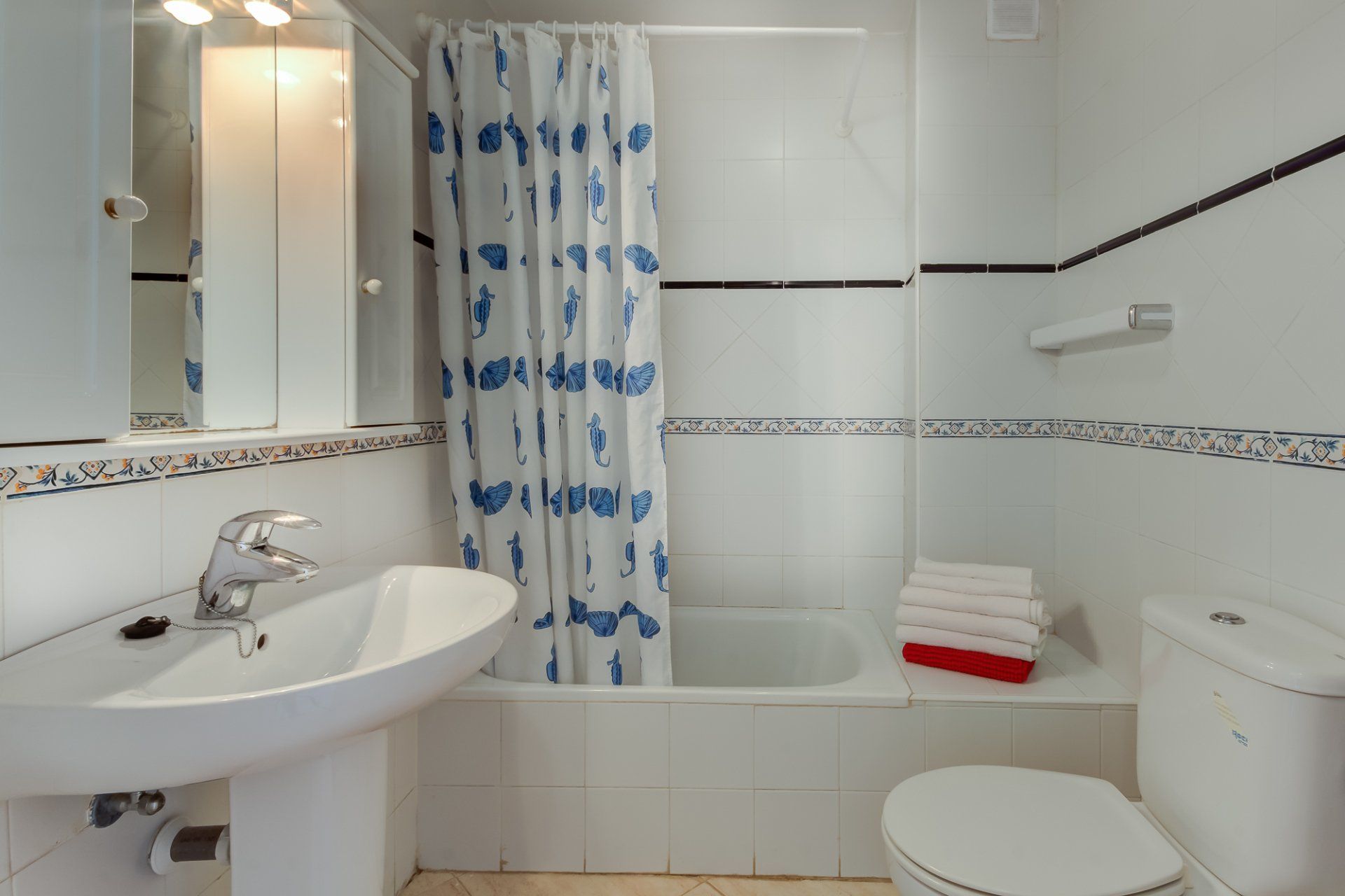 bathroom with bath and shower over and blue and white shower curtain