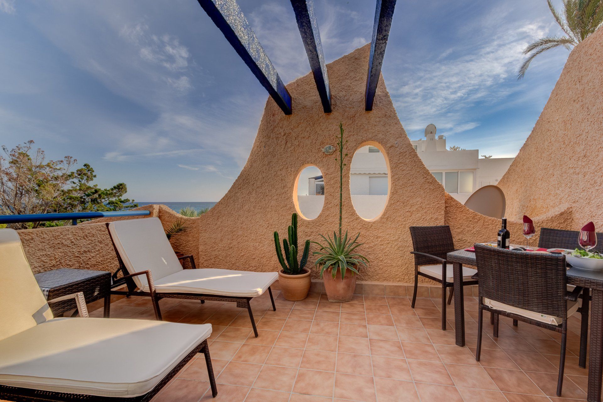 main terrace with two sunloungers on the left and table and chairs set for lunch on the right