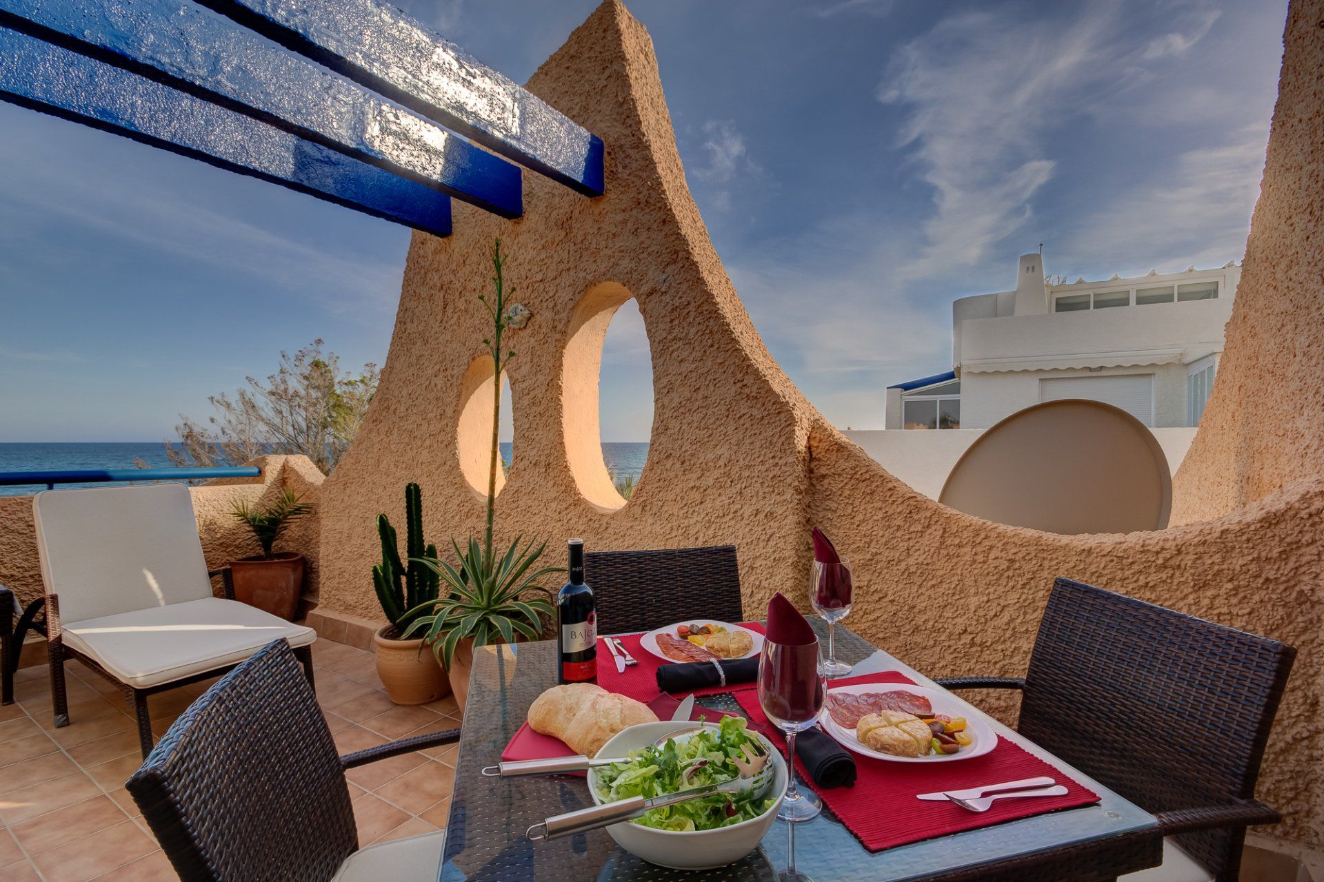 on the main terrace with the dining table in the foreground with lots of tapas and a bottle of red wine and wine glasses