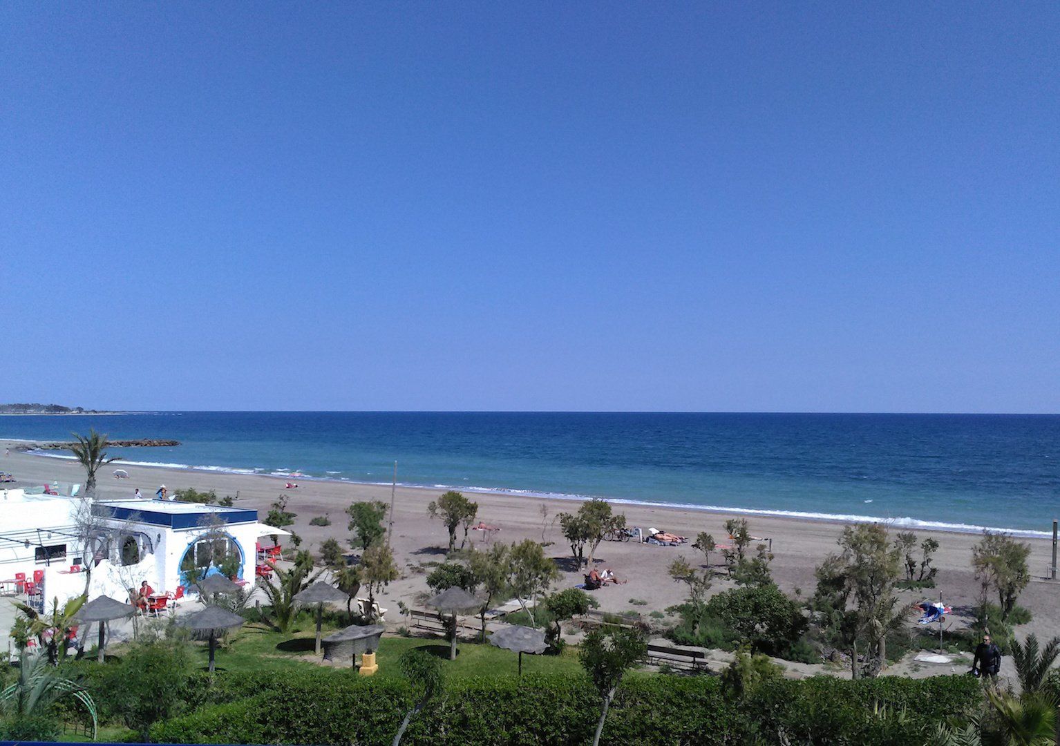 view from terrace looking down onto beach bar and beach and sea