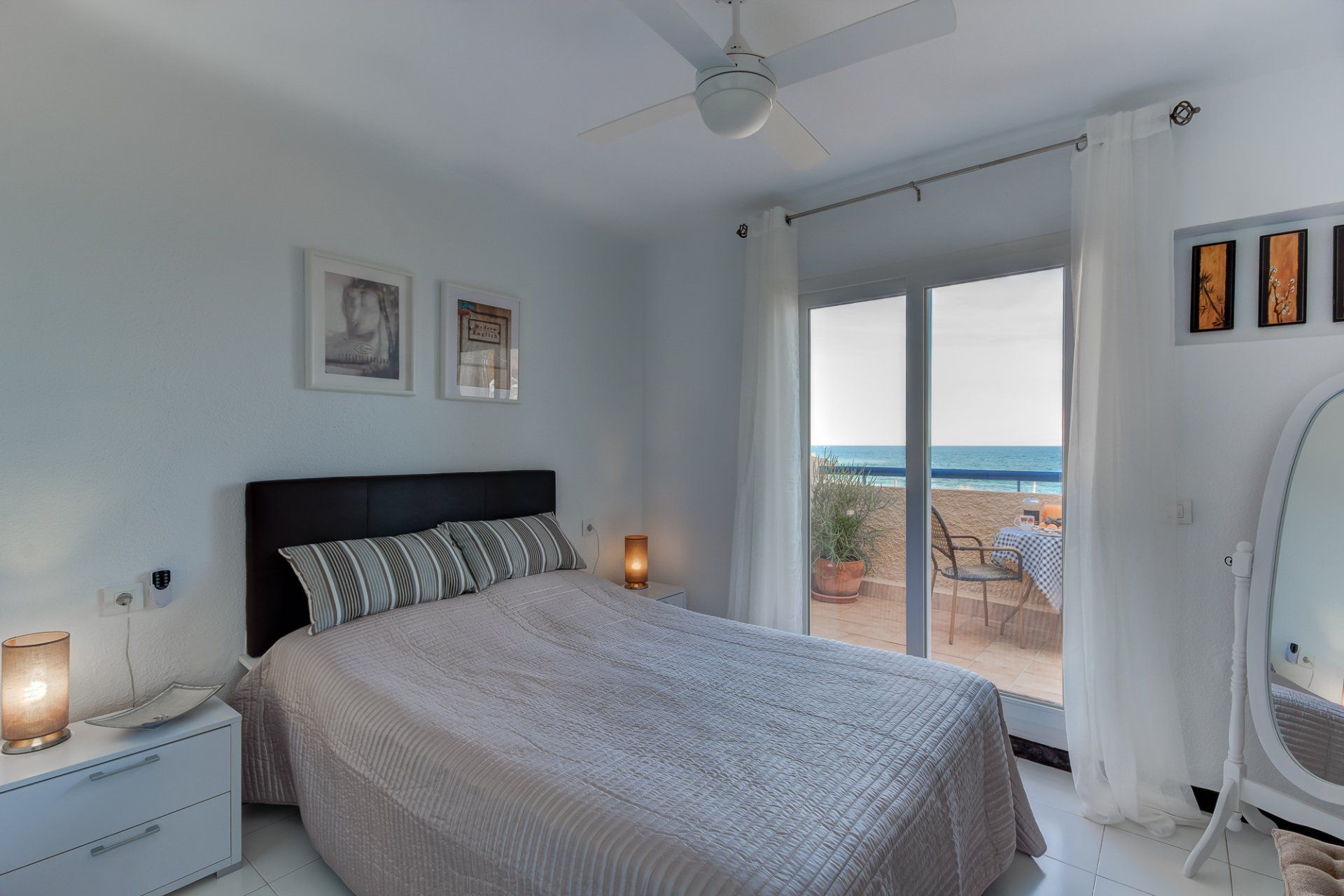 bedroom with comfy looking double bed and patio doors onto terrace with sea views