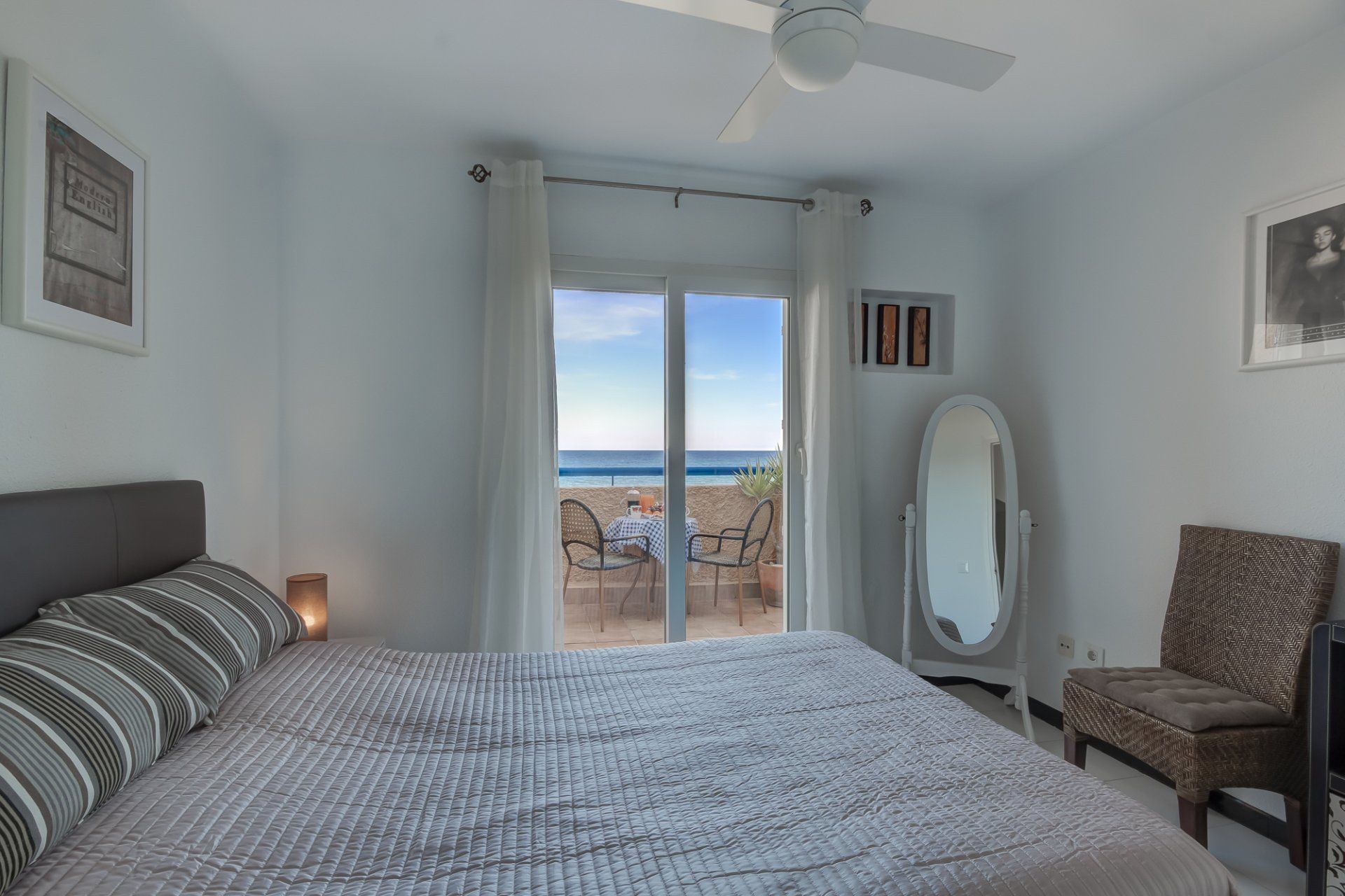 bedroom with double bed and lovely bedding with patio doors leading to terrace with sea views