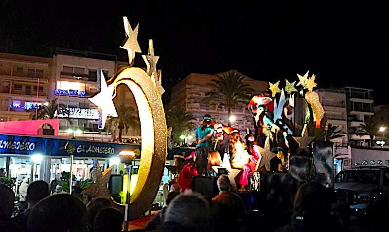 night time and a big carnival float lit up with people on it dressed as the three kings