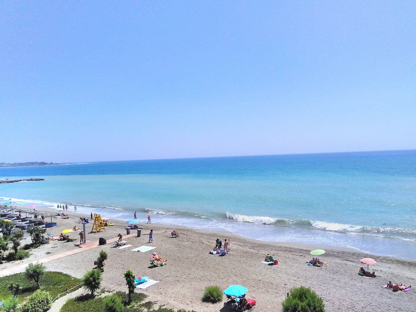 taken from above looking down onto the sandy beach with lots of people sunbathing and enjoying the beach
