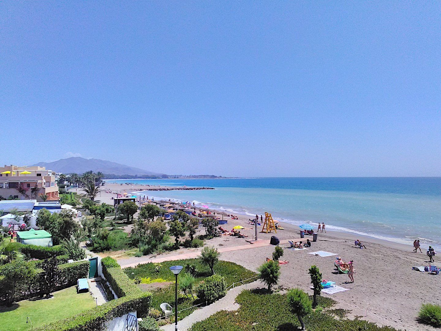 a view taken from above of the beach looking north and there are lots of people sunbathing and enjoying themselves