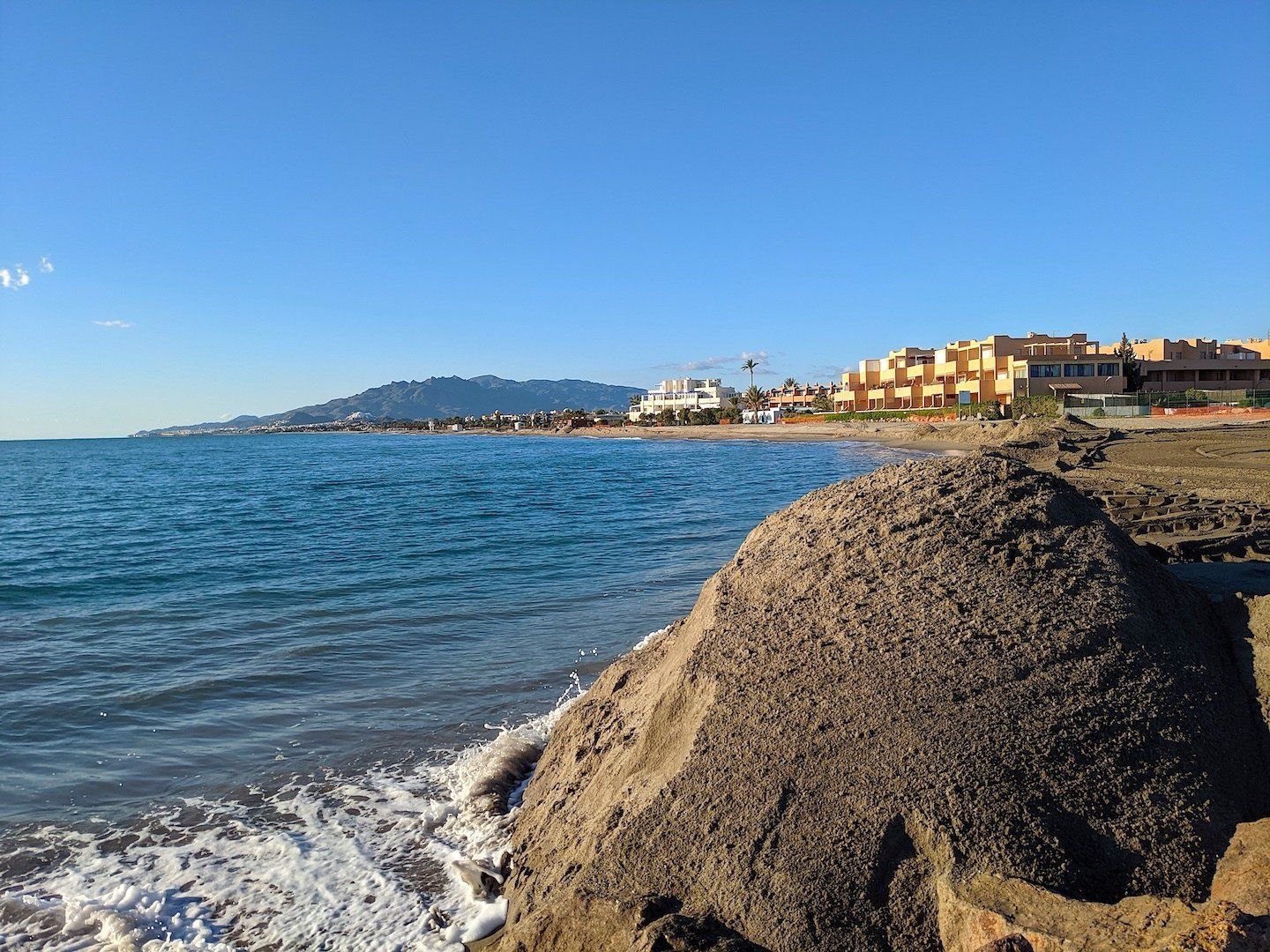 huge piles of sand mountains on the waters edge ready to be smoothed in