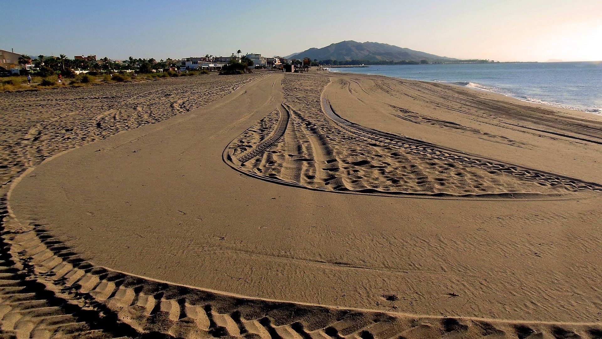 a close up of generous looking sand freshly raked and golden with the rest of the beach in the background