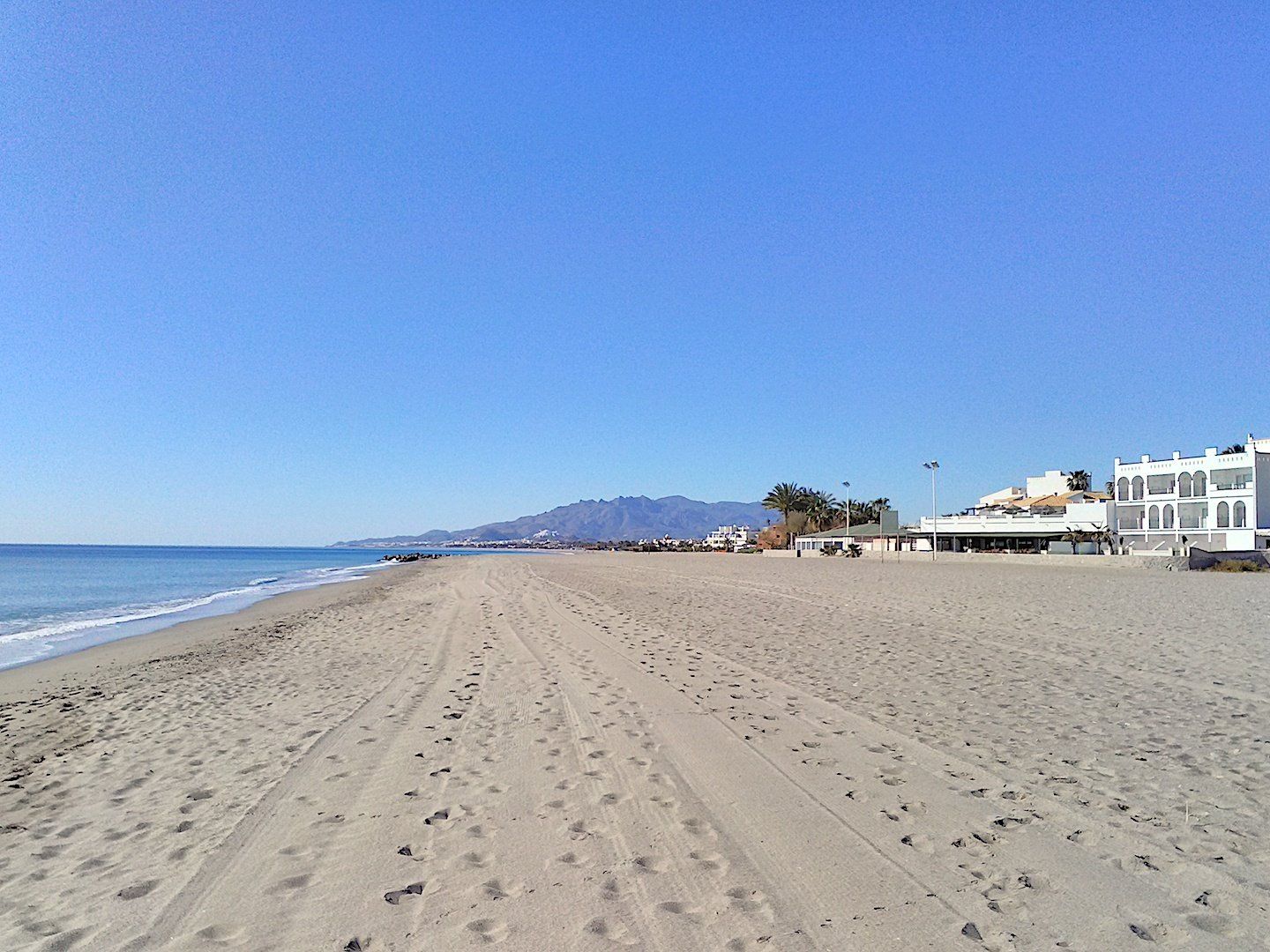 the naturist hotel is directly on the sand to the right and the beach stretches for miles in the distance