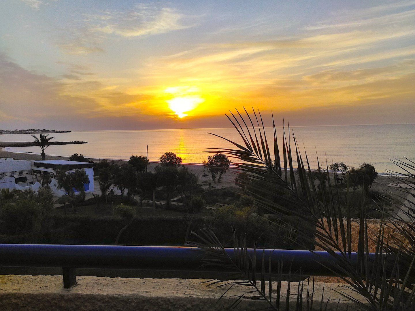 at dawn looking out to the with the sun rising on the distant horizon setting the sky alight in orange and yellow