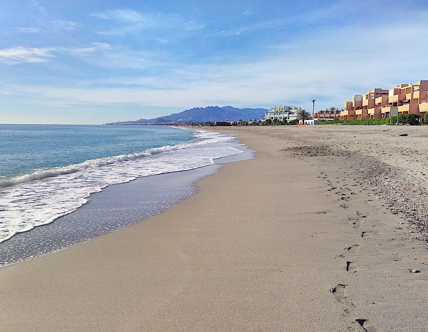 long sweep of the sandy beach with soft looking sand and surf