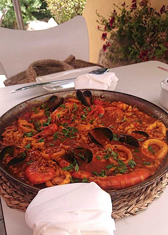 close up of a huge dish of paella on a white table cloth