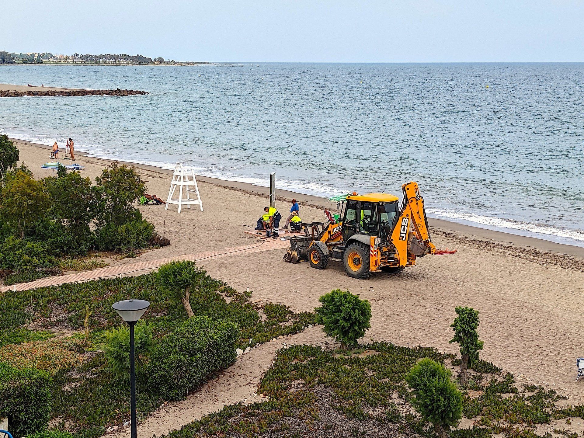 men and machinery putting the new shower in place on the beach