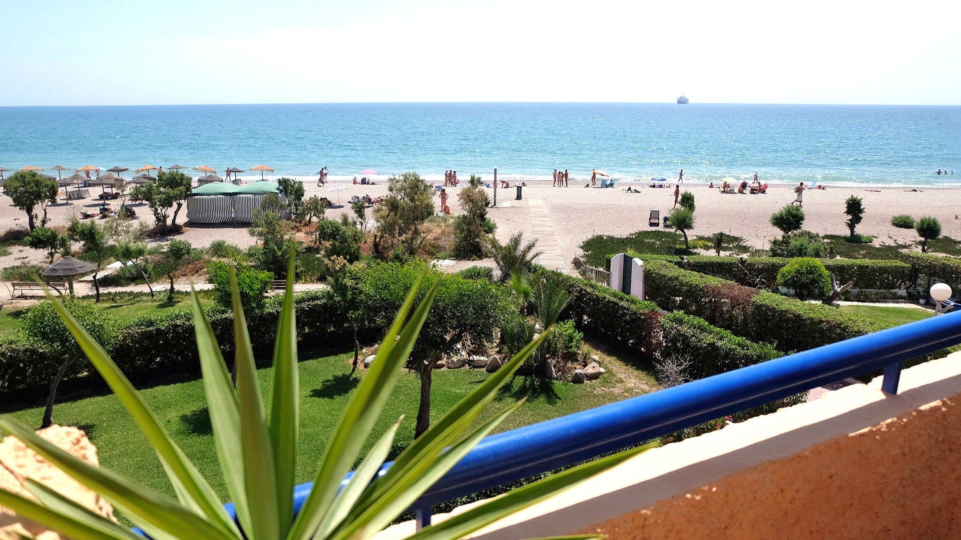 looking over the terrace and to the beach below on a sunny day with lots of people on the beach