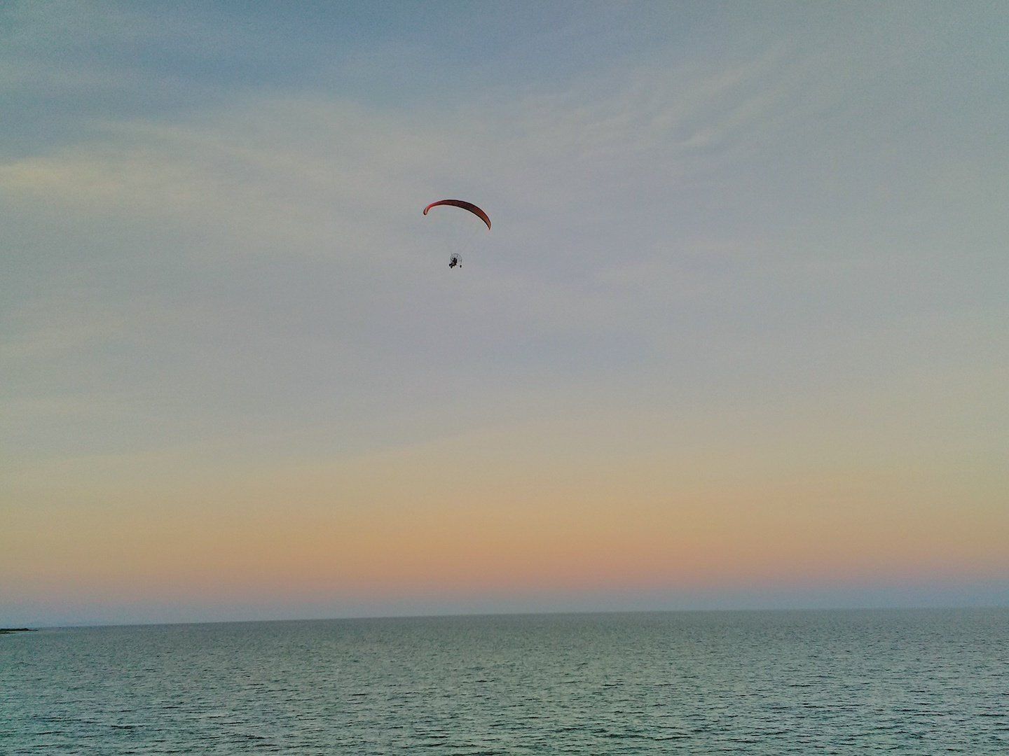 a hanglider soars high above the sea