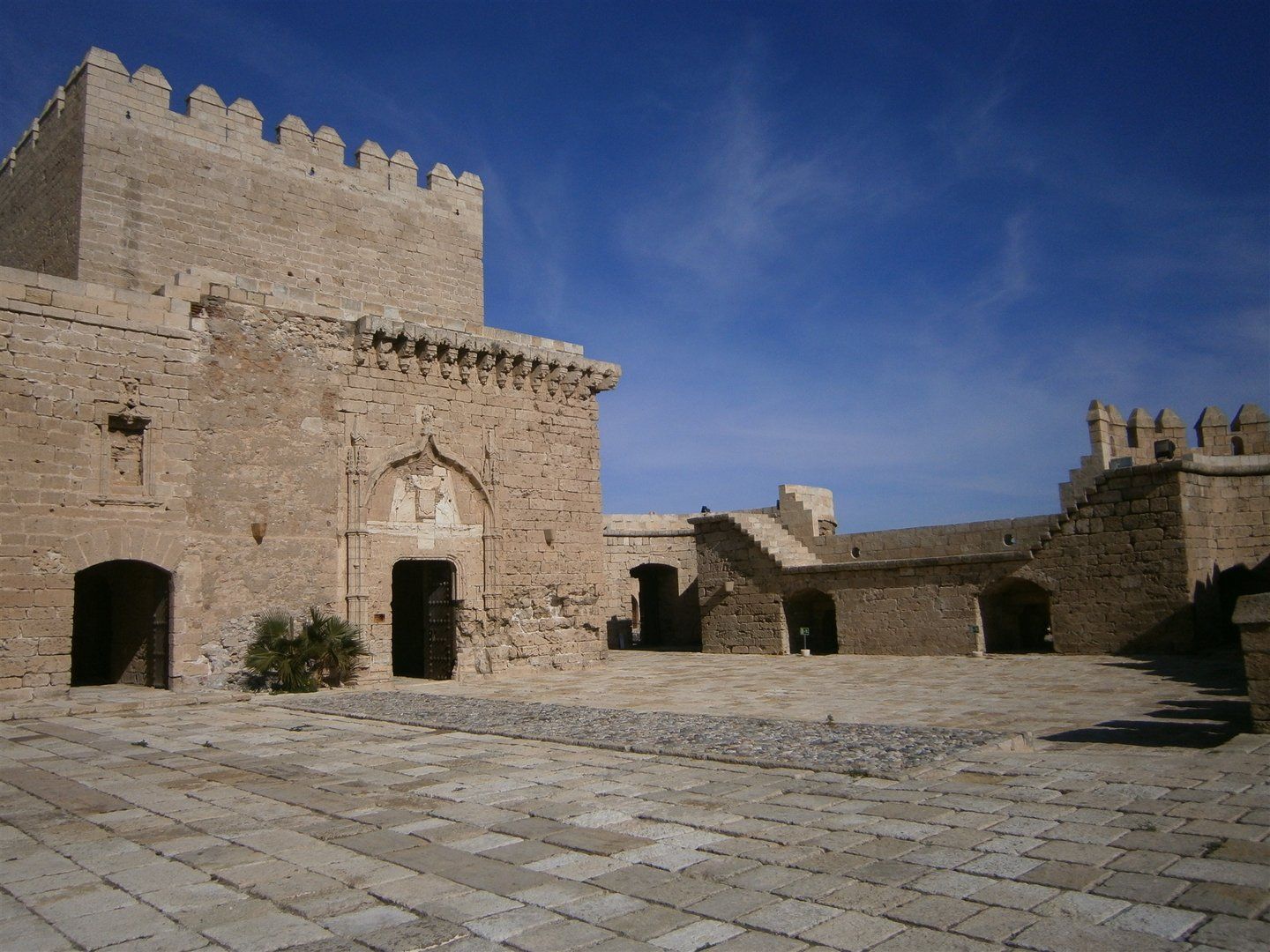 section of restored ancient castle and stone floor courtyard with walls