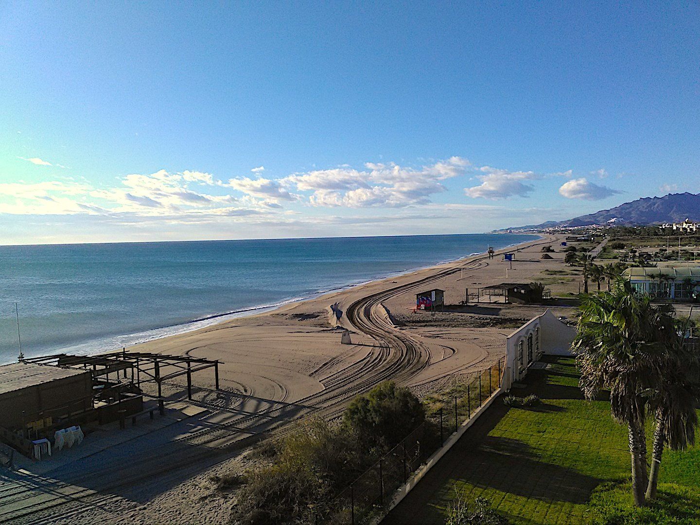 long view of beach showing huge track marks left behind by the dumper trucks all the way along the beach