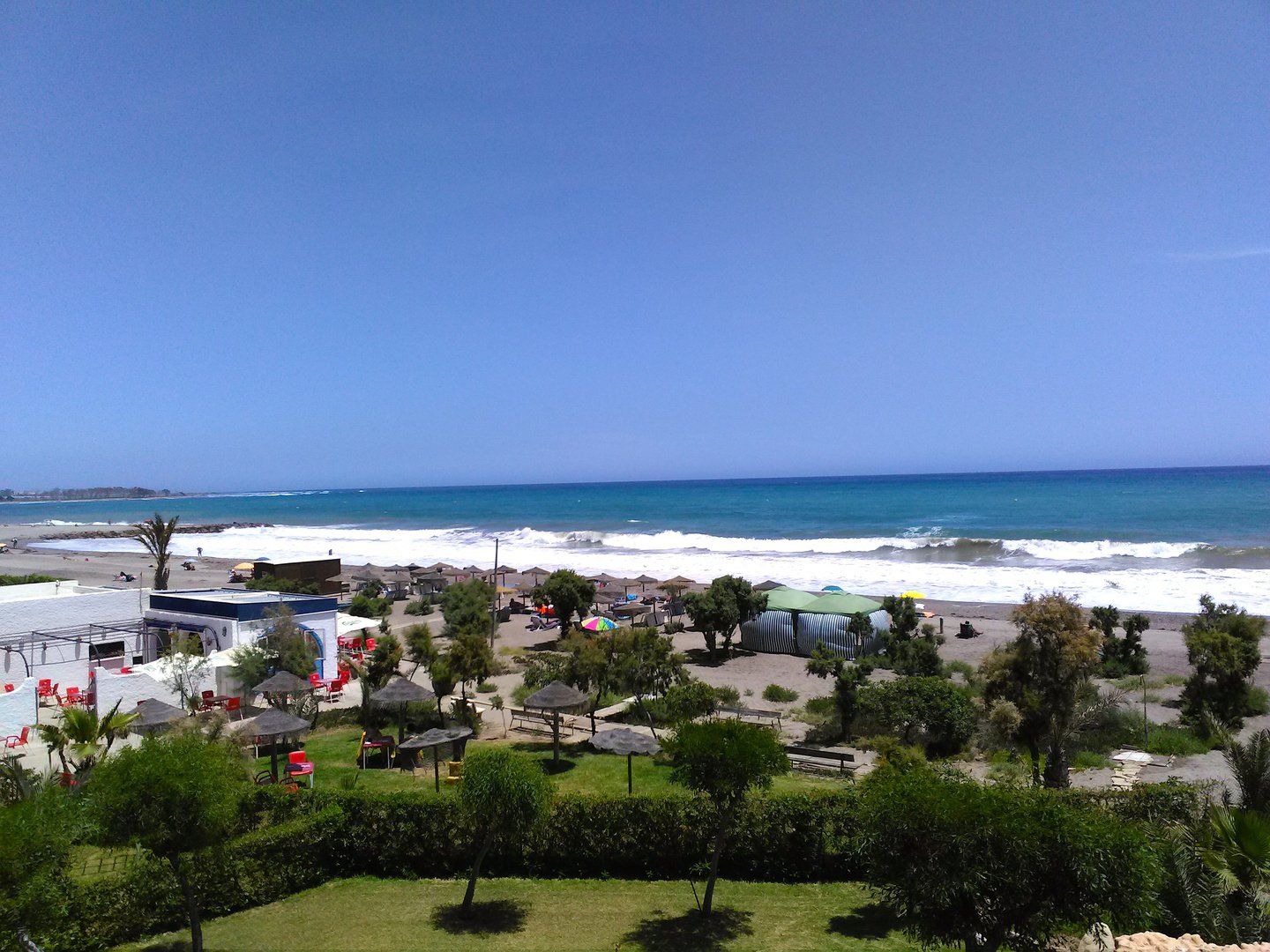 View of the beach and beach bar with waves on the shoreline