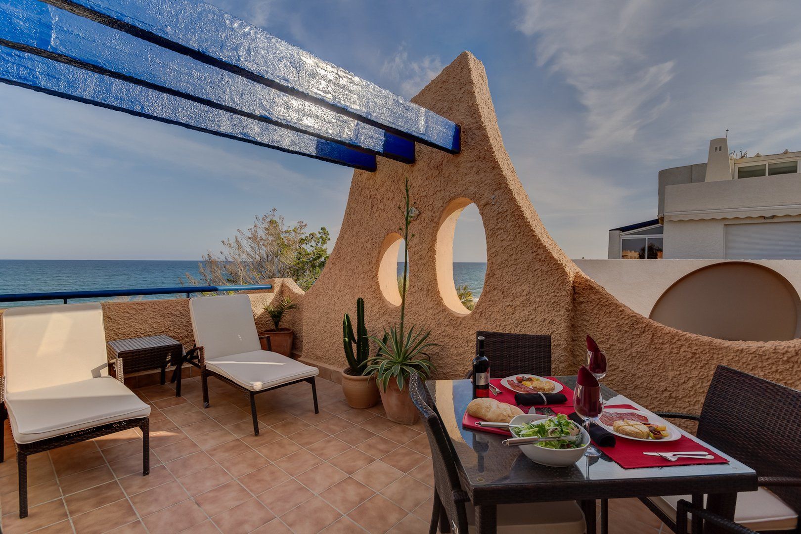 a daytime photo of the same terrace but with no fairy lights or anything just the table chairs and sunloungers