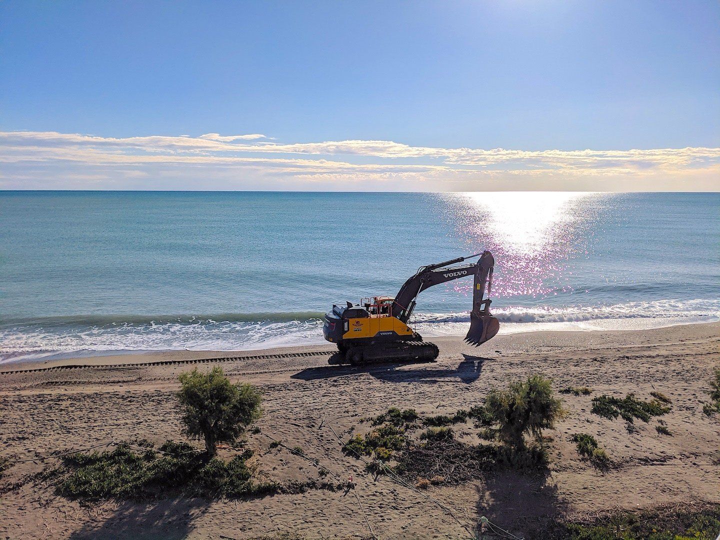 a big commercial digger by the waters edge digging into the sand