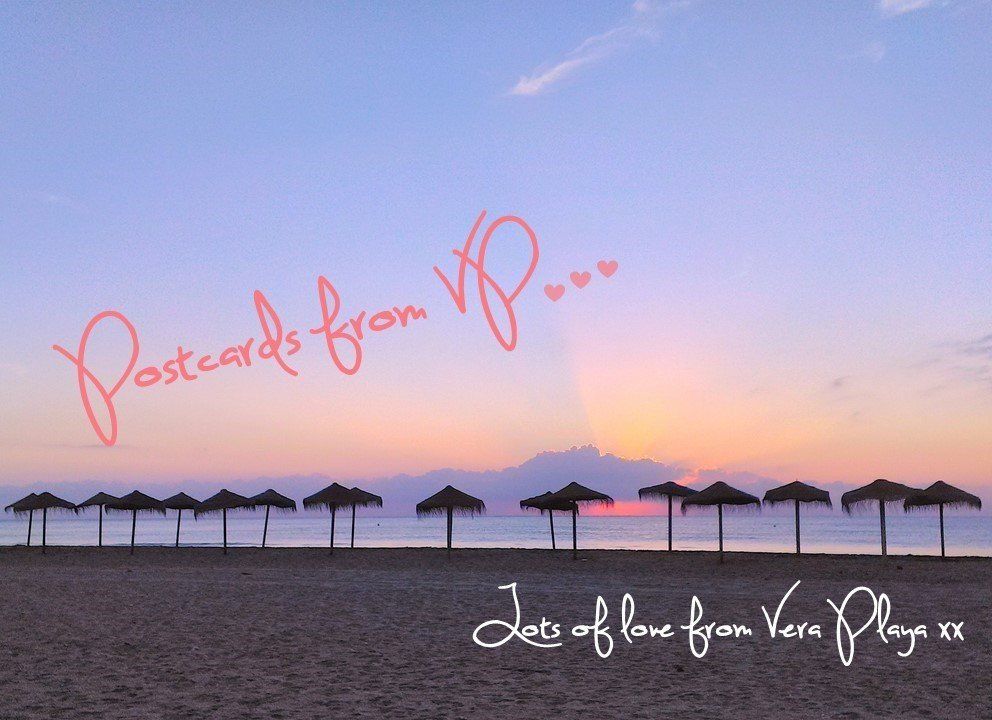 beach at dawn with pink sun rise diffusing through fluffy clouds and thatched sun parasols on shoreline