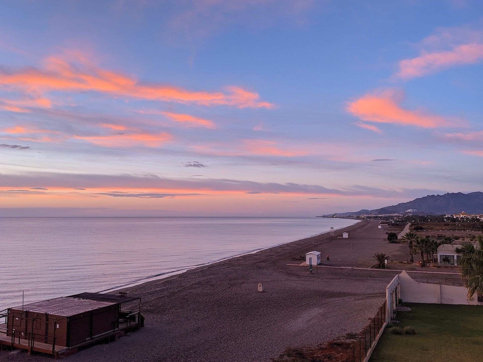 looking down onto the beach and the sea reflects the blue and pink sky
