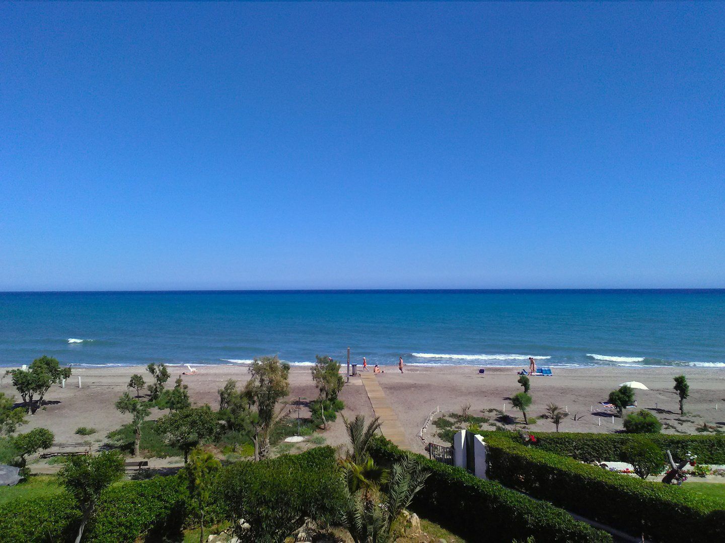 looking down onto the naturist beach below and the main path with a few naked people in the distance