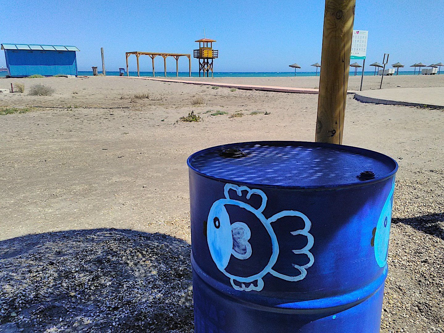 old oil barrel painted bright blue with a funny looking fish painted on it