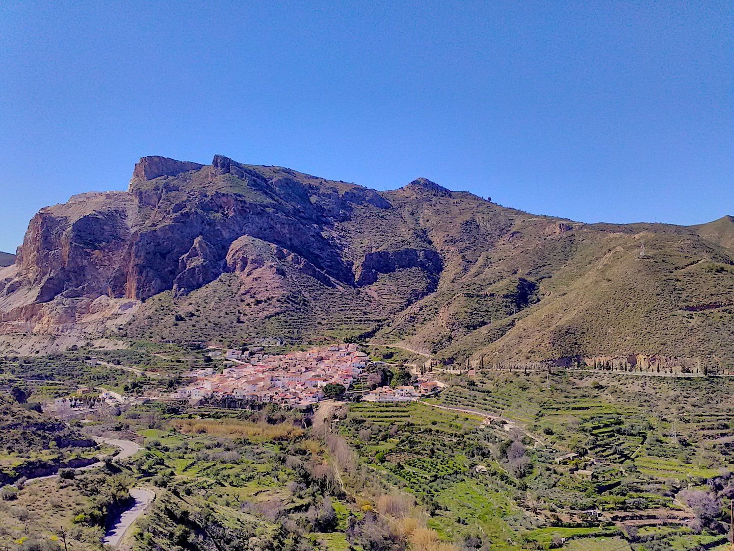 Mountain terrain with a little white traditional looking village nestled amoung the mountains