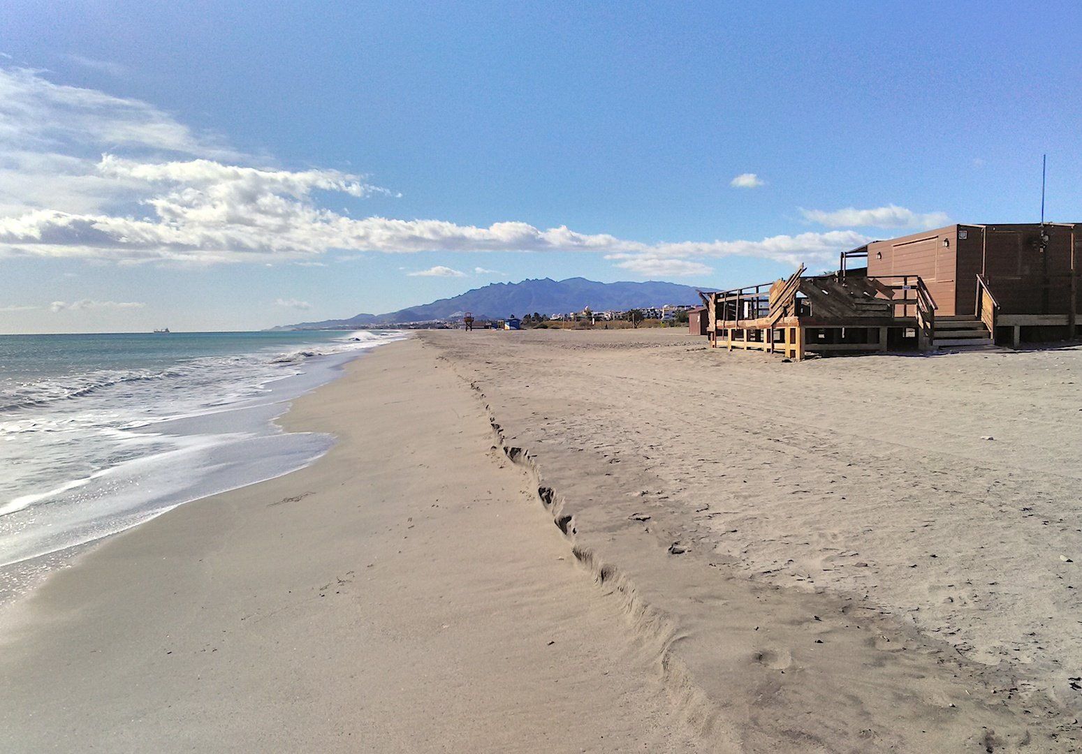 wide sandy beach with a little beach bar to the right and the sea to the left