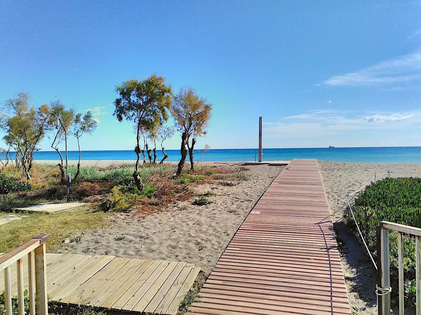 a rustic wooden plank walkway across the sand at the entrance to the vera playa naturist beach