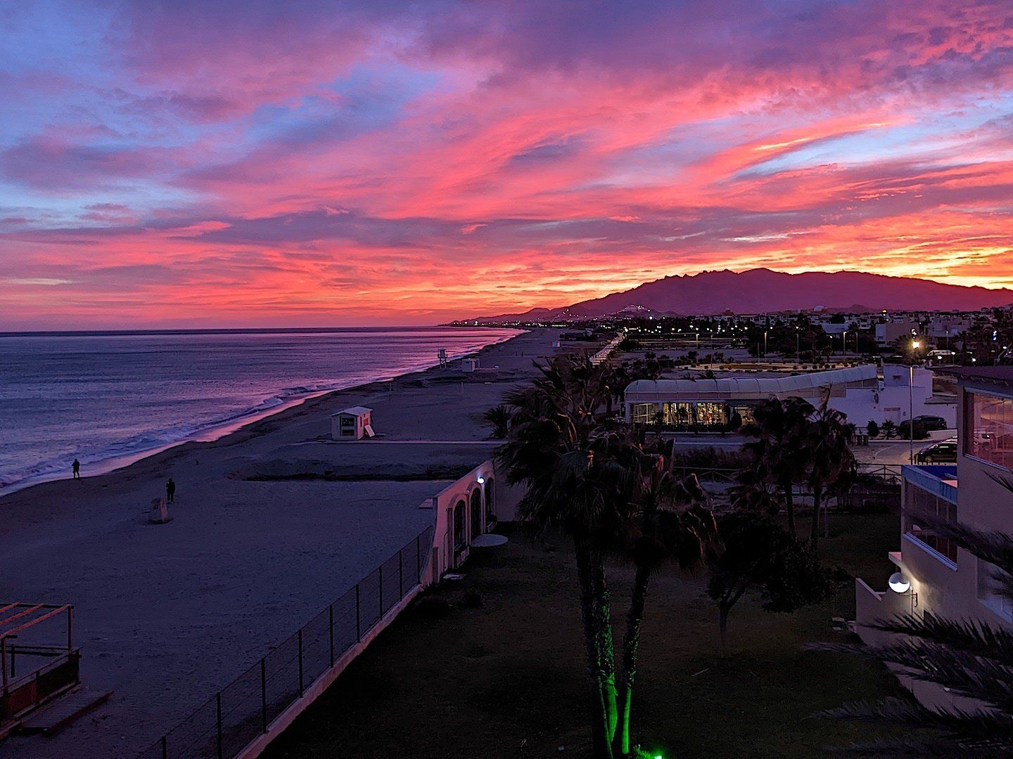 Looking across the beach and out to the mountains at dusk and the purple sky makes everything blue and purple with lights on in buildings by the beach
