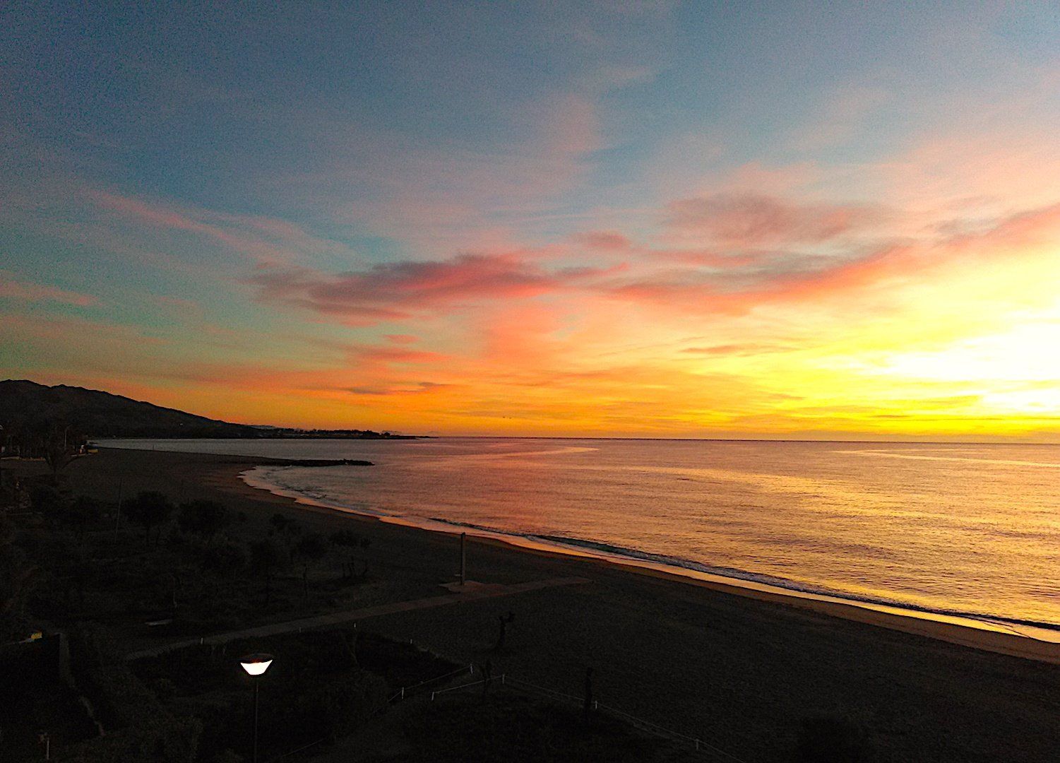 the beach at sunrise the horizon is yellow and gold and these colours reflect onto the sea