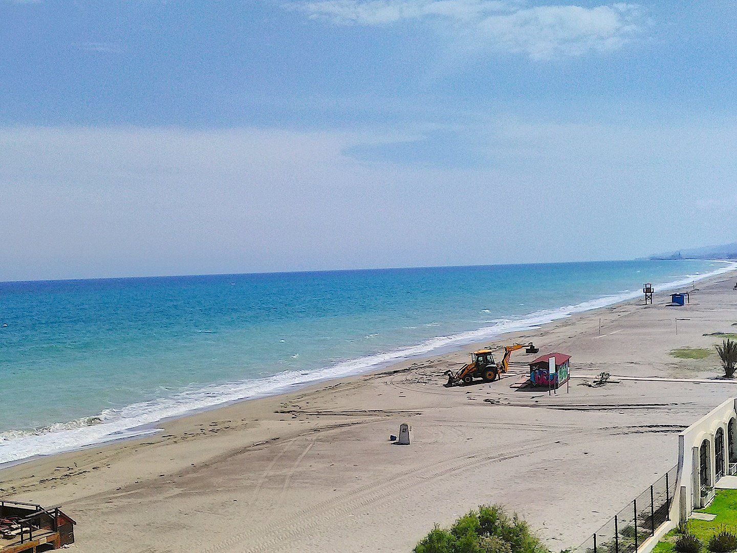 the beach and in the distance are two diggers making repairs