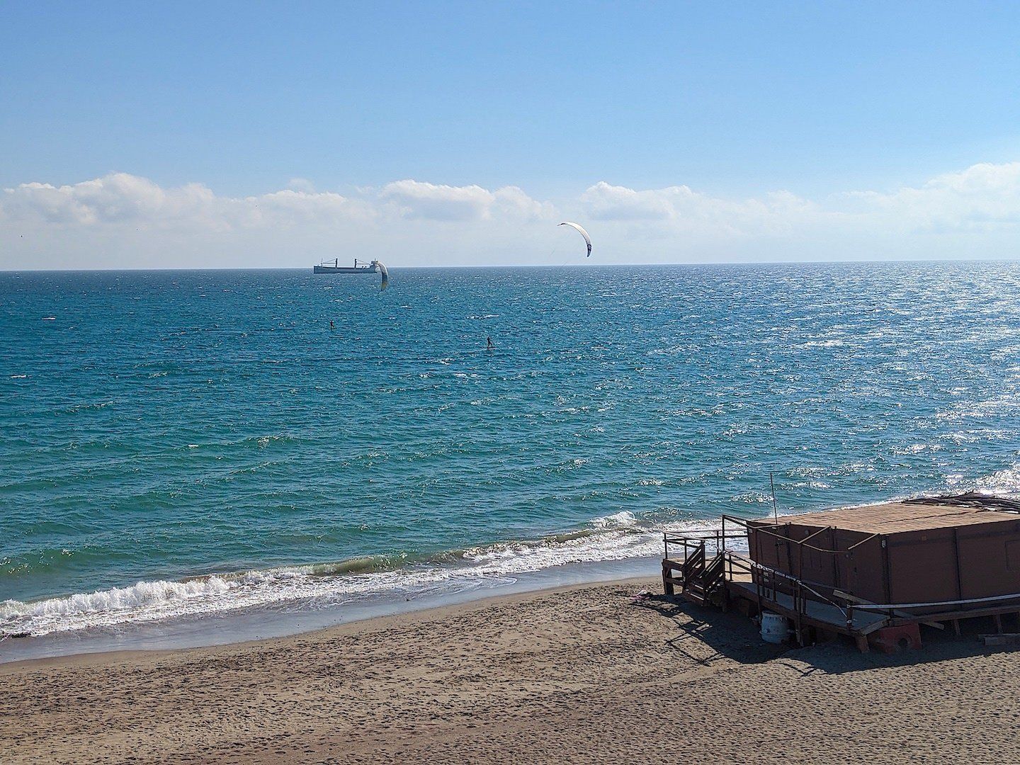 looking out across sparkling sea with two kite surfers out on the water