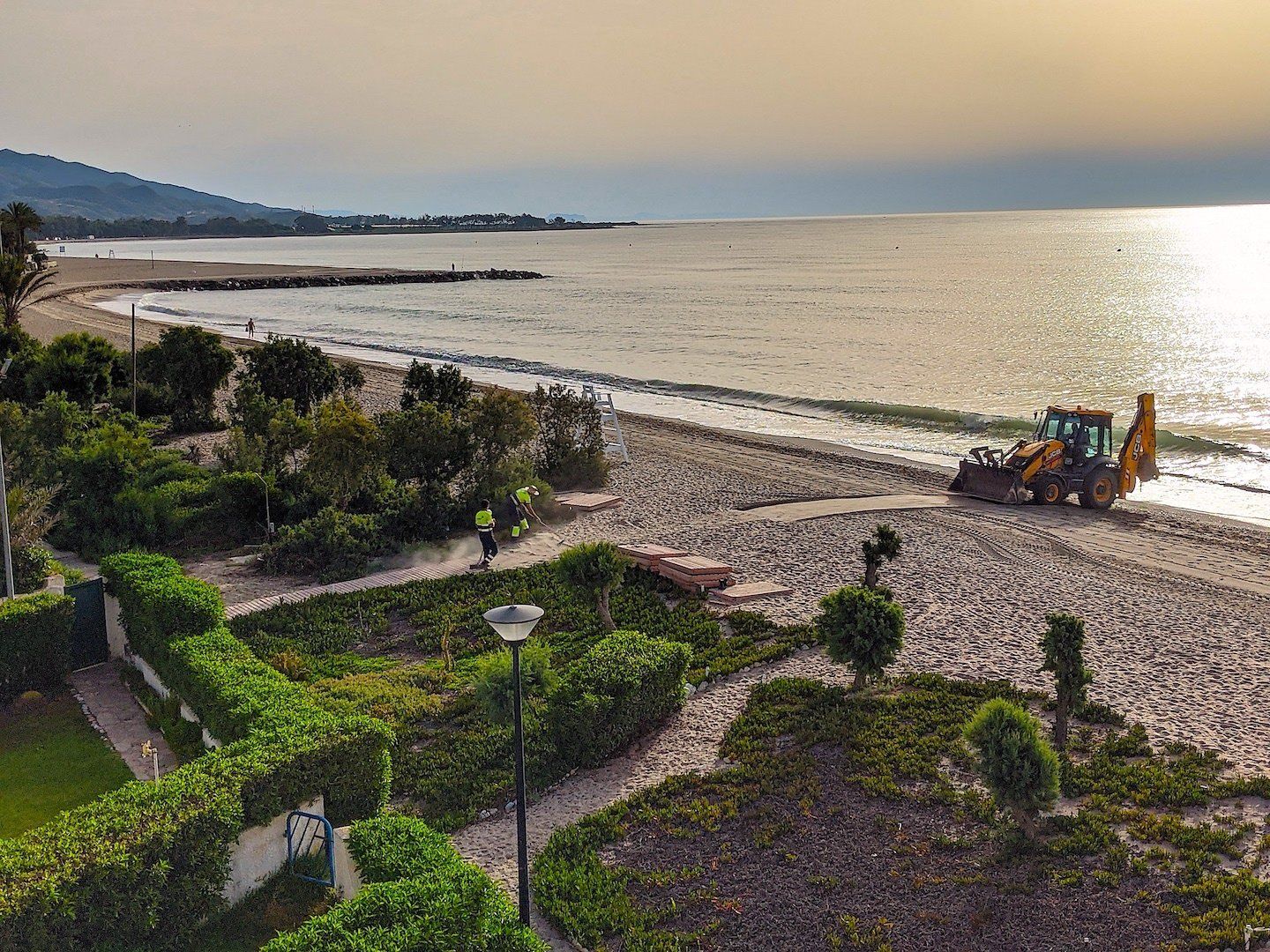 men and machinery on the beach below mending a boardwalk style path on the sand