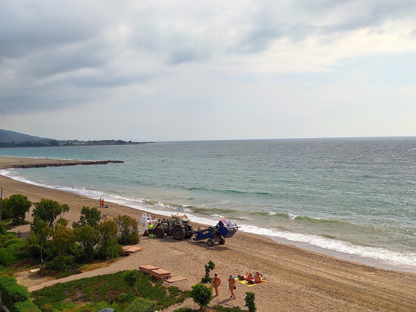 a big tractor carries a lifeguard tower on its front forks into place across the beach