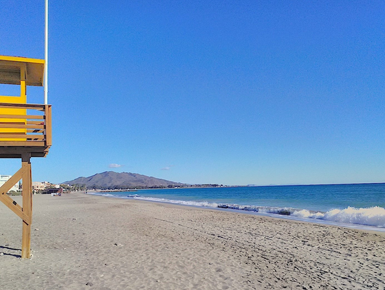 the famous yellow vera playa lifeguard tower partly visible on the left with the sweep of the bay  behind it